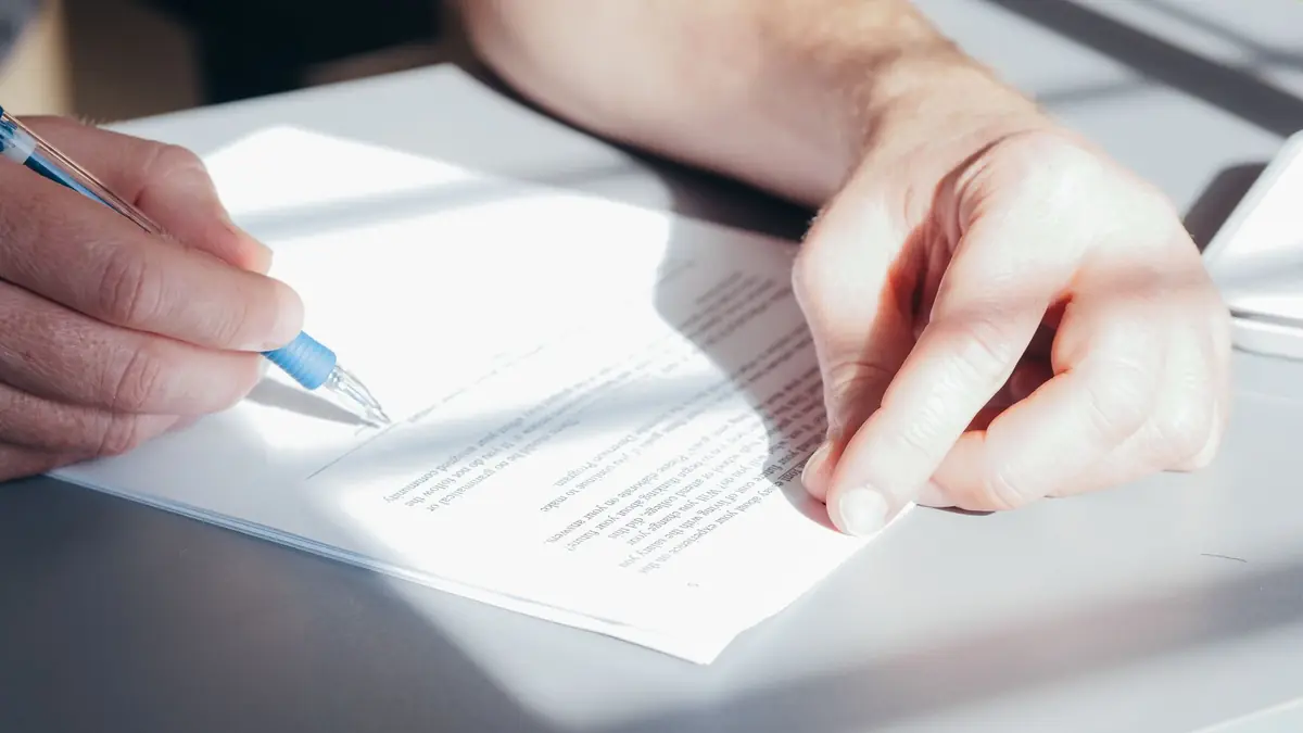 Hands signing a contract with a blue pen, close-up view, illustrating how to advertise Botox legally in 2026