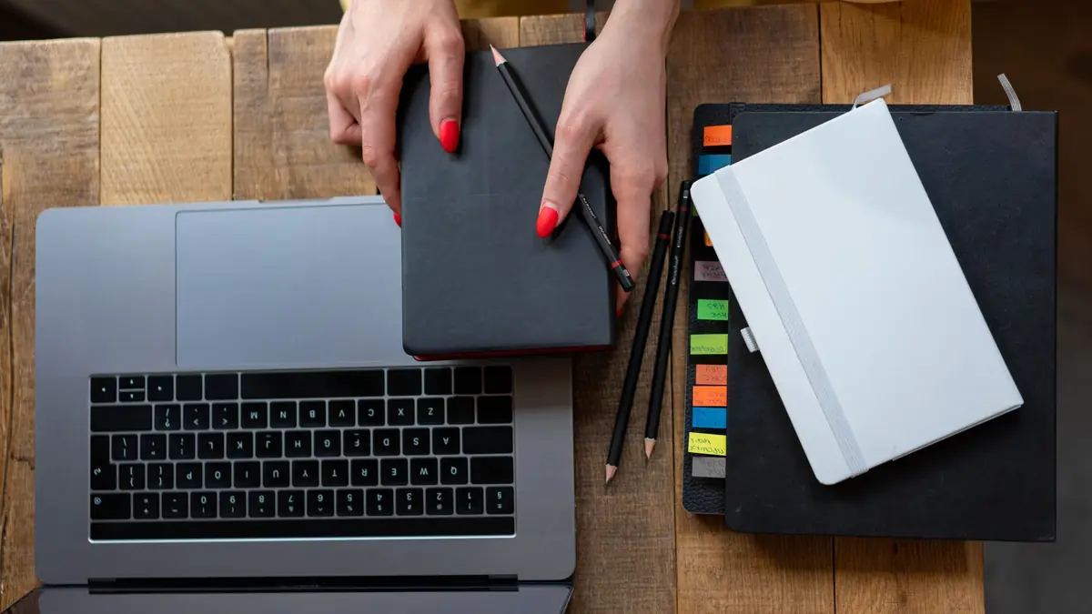 Top-down view of a desk with laptop, planner, and notebooks. Perfect for business and productivity themes, illustrating how to write a med spa business plan