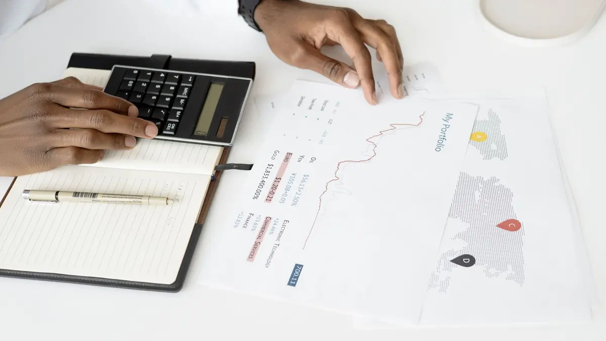 Overhead view of a person analyzing financial documents using a calculator for investment planning, illustrating med spa marketing budget