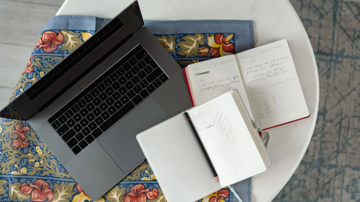 Overhead shot of a laptop with notebooks and a pencil on a patterned cloth, illustrating how to build a med spa marketing plan