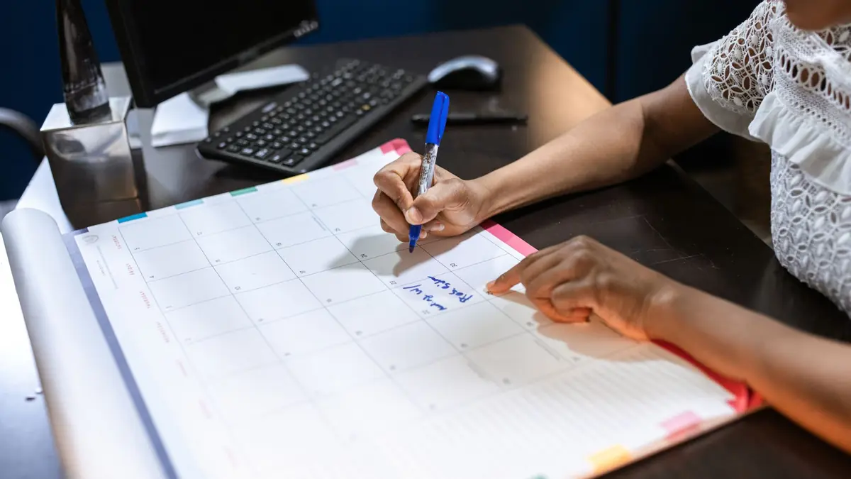 Person writing important notes in a desk calendar with a pen, set in an office, illustrating new med spa marketing